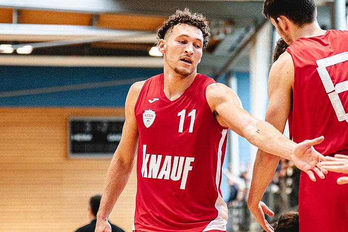 Das Foto zeigt Baskets-Spielmacher Brae Ivey in Nahaufnahme, wie er einen Teamkollegen abklatscht. 