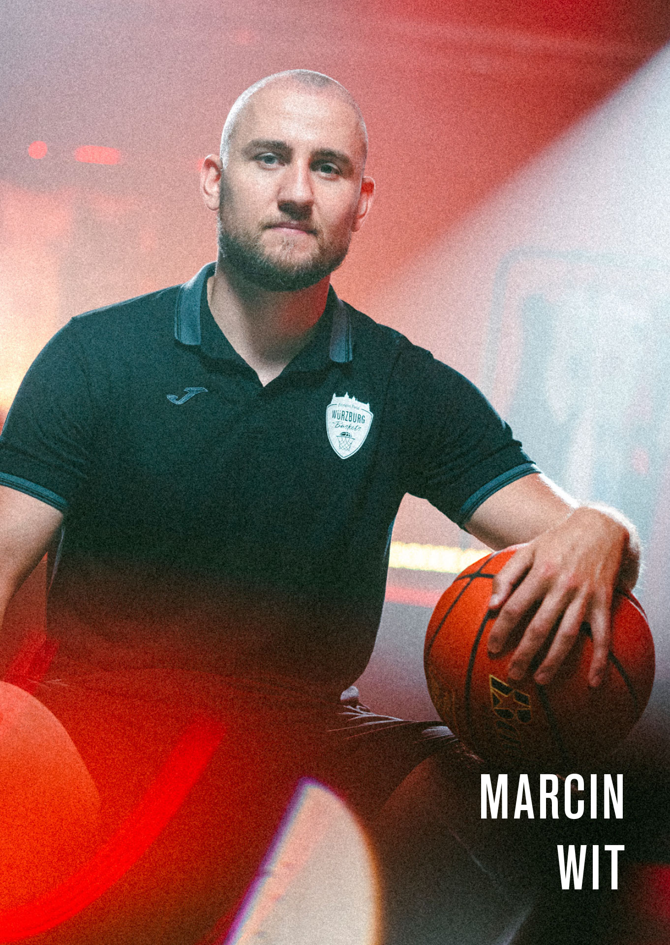 Assistant Coach Marcin Wit lächelt in die Kamera mit einem Basketball im Arm